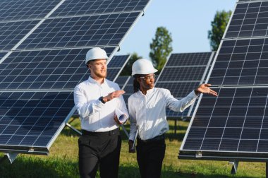 Çeşitli mühendisler yenilenebilir enerji projesini tartışıyor, büyük bir güneş enerjisi santralinde birlikte çalışıyorlar.