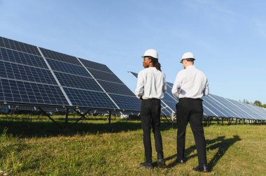 Sert şapka takan iki mühendis güneş enerjisi üretimini yönetiyor, sürdürülebilirlik ve yeşil teknolojiye odaklanıyor