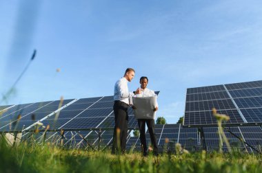 İki mühendis bir planla yeni güneş paneli kurulumunu tartışıyor. Temiz yenilenebilir enerji kavramı