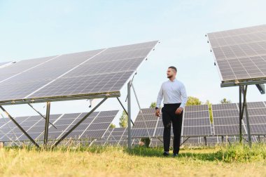 Güneş panelleri arasında yürüyen mühendis yenilenebilir enerji üretimini inceliyor. Yeşil enerji ve sürdürülebilirlik kavramı