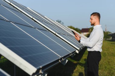 Yenilenebilir enerji için güneş panellerini izlemek ve denetlemek için dijital tablet kullanan mühendis