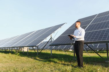 Adam güneş çiftliği performansını tablet kullanarak izliyor, sürdürülebilir enerji ve yeşil teknolojiyi destekliyor