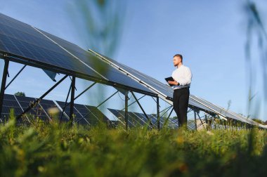 Mühendis, güneş panellerini akıllı tabletle izliyor, verimli yeşil enerji üretimi ve sürdürülebilir teknoloji geliştirmesini sağlıyor