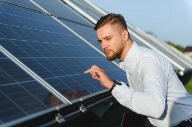 Adam güneş panelini kontrol ediyor, yenilenebilir enerji, sürdürülebilir teknoloji ve profesyonel bakımı temsil ediyor.