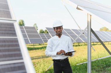 Başlık takan ve elinde tablet tutan mühendis büyük bir güneş enerjisi santralinin işletmelerini yönetiyor.