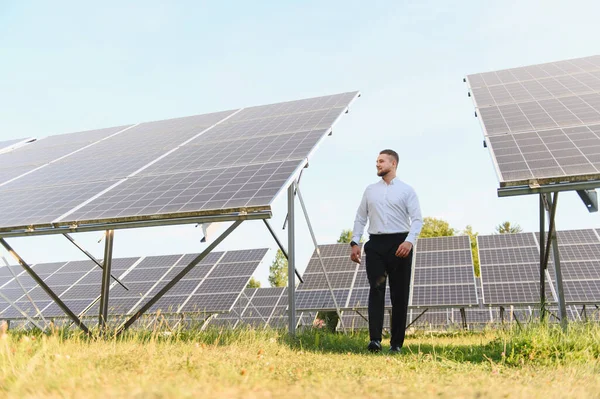 Güneş panelleri arasında yürüyen mühendis yenilenebilir enerji üretimini inceliyor. Yeşil enerji ve sürdürülebilirlik kavramı