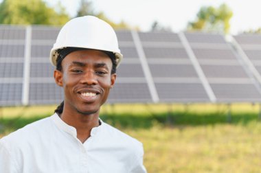 Güneş paneli sahasında dikilip yenilenebilir enerji ve sürdürülebilirliği destekleyen Afrika kökenli Amerikalı mühendis.