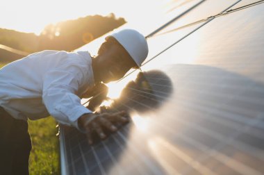 Günbatımında güneş panellerini kontrol eden mühendis verimli sürdürülebilir yeşil enerji üretimi ve çevresel koruma sağlıyor