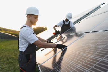 Bir güneş enerjisi santralinde fotovoltaik modüller oluşturan işçiler, yenilenebilir ve temiz enerji çözümleri sunuyorlar