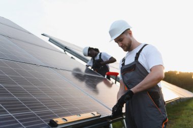 Bir güneş enerjisi santraline güneş panelleri kuran işçiler daha parlak bir gelecek için sürdürülebilir yeşil enerji üretiyor.
