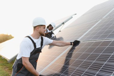 Mühendisler güneş çiftliğine fotovoltaik modüller kuruyorlar, temiz, yenilenebilir enerji üretiyorlar. Yeşil teknolojinin geleceğine odaklan