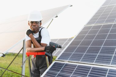 Genç adam yenilenebilir enerji istasyonuna güneş panelleri kuruyor. Sürdürülebilir bir gelecek için çalışmak