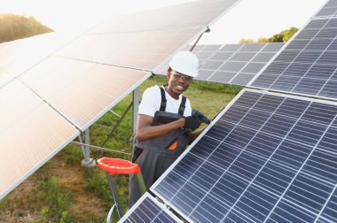 Afrikalı Amerikalı bir adam güneş paneli kuruyor, yenilenebilir enerji üretimine ve sürdürülebilirliğe katkıda bulunuyor