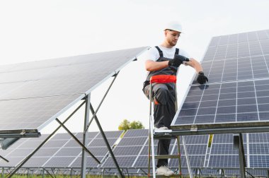 Güneş panellerini güneş çiftliğine kuran teknisyenler, sürdürülebilir gelecek için temiz enerji üretiyorlar.