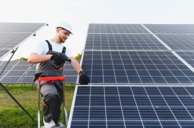 İşçi güneş panelleri kuruyor, sürdürülebilir elektrik üretimini sağlıyor ve yenilenebilir enerji gelişimine katkıda bulunuyor