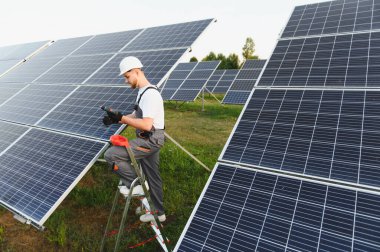 Sahaya güneş paneli kuran bir merdivendeki teknisyen yeşil ve sürdürülebilir enerji üretimine katkıda bulunuyor.