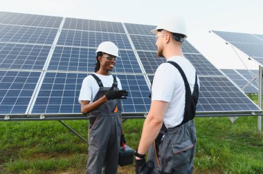 Çeşitli mühendisler devam eden bir projeyi, yenilenebilir güneş enerjisi sistemlerinin kurulmasını ve sürdürülmesini tartışıyor.