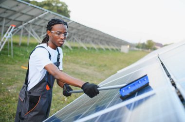 Afrika kökenli Amerikalı işçiler güneş panellerini fırçayla temizliyor ve güneş çiftliklerinde verimli yenilenebilir enerji üretimini sağlıyorlar.