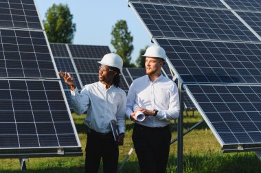 Güneş panellerini inceleyen çeşitli mühendisler yenilenebilir enerji çözümleri ve sürdürülebilir enerji üretimini tartışıyorlar.
