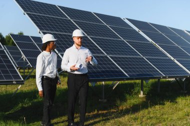 Güneş panelleri sıralarını denetleyen, sürdürülebilir bir gelecek için yenilenebilir enerji üretimi planlayan sabit başlıklı mühendisler