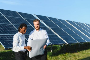 Çeşitli mühendisler bir güneş enerjisi santralinin planını gözden geçiriyorlar, yenilenebilir enerji sistemi uygulaması planlıyorlar