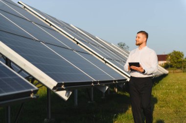 Adam, sürdürülebilir enerji üretimi ve yeşil teknoloji çözümleri sağlayan bir tabletle güneş paneli kurulumunu izliyor