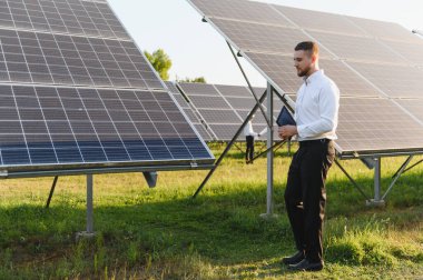 Dijital tablet taşıyan bir güneş enerjisi istasyonunu teftiş eden mühendis. Yeşil teknoloji ve sürdürülebilirlik için yenilenebilir enerji kavramı