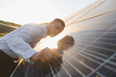 Genç adam bir alanda güneş panelini kontrol ediyor, yenilenebilir enerji teknolojisi ve sürdürülebilir iş geliştirme gösteriyor