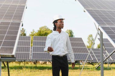 Güneş paneli alanını inceleyen erkek mühendis, sürdürülebilir enerji üretimi ve gelecekteki yeşil gelişimi güvence altına alıyor