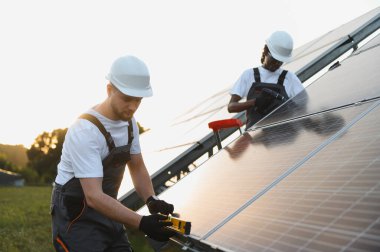 İki farklı mühendis fotovoltaik modüller kuruyor, sürdürülebilir güç üretimi için hassas hizalama ve bağlantı sağlıyorlar