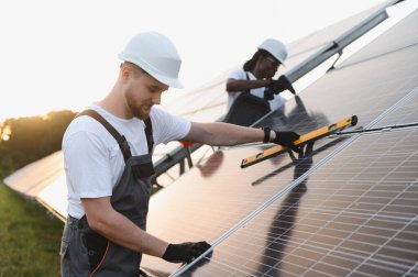 Fotovoltaik paneller kuran mühendisler, sürdürülebilir bir enerji santralinde verimli yeşil enerji üretimi için uygun hizalamayı sağlıyorlar.