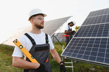 Bir güneş enerjisi santraline güneş paneli sistemi kuran işçiler, temiz elektrik üretimine ve sürdürülebilir enerji gelişimine katkıda bulunuyorlar