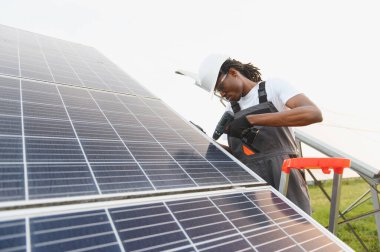 Güneş panelleri kurmak için matkap kullanan işçiler, sürdürülebilir enerji ve gelecekte güç şebekesini düzeltmeye katkıda bulunuyorlar