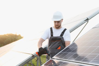Bir güneş enerjisi santralinde sürdürülebilir elektrik üretimi için güneş panelleri kuran bir teknisyen.