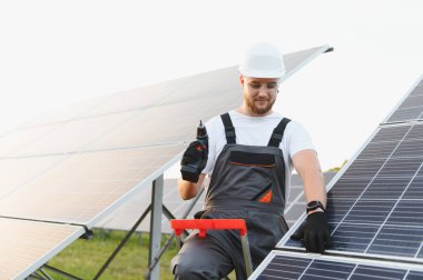 Koruyucu ekipman giyen işçiler, fotovoltaik paneller kuruyor ve sürdürülebilir kalkınma için yenilenebilir enerji üretimine katkıda bulunuyor