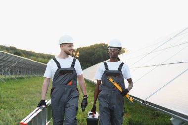 Çeşitli mühendisler alet ve merdiven taşıyıp yenilenebilir enerji çiftliğine güneş panelleri yerleştirecek ya da onaracak.