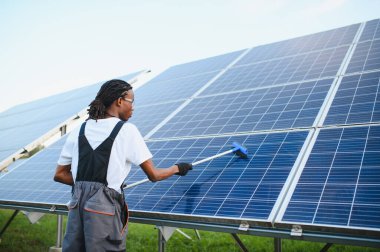 Bir elektrik santralinde güneş panellerini temizleyen teknisyen sürdürülebilir yeşil enerji üretimi için bakım yapıyor.