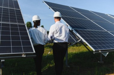 Güneş panellerini inceleyen, sürdürülebilir bir yeşil enerji girişimi planlayan ve yöneten iki farklı mühendis.