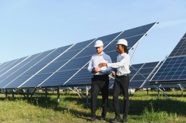 İki mühendis, yenilenebilir enerji çözümlerini ve bir güneş enerjisi santralinde proje planlarını tartışıyorlar.