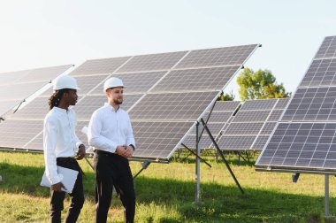 Güneş panellerini kontrol eden çeşitli mühendisler, sürdürülebilir teknoloji ve yeşil enerji üretimini tartışıyorlar