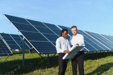 Bir güneş çiftliğinin planlarını tartışan iki mühendis sürdürülebilir enerji ve yenilenebilir enerji üretimini planlıyorlar.