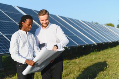 Mühendisler bir güneş enerjisi santralinde sürdürülebilir enerji çözümleri planlayarak bir plan üzerinde çalışıyorlar.