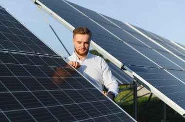 Güneş panellerini inceleyen genç adam, sürdürülebilir temiz enerji üretimi için optimal performans sağlıyor