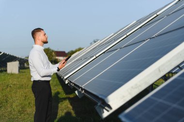 Güneş paneli performansını kontrol eden erkek mühendis, sürdürülebilir enerji üretimini ve teknolojik gelişmeleri güvence altına alıyor.