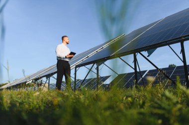 Güneş enerjisi üretimini bir güneş çiftliğinde izleyen adam yenilenebilir teknoloji ve sürdürülebilir enerji üretimini vurguluyor