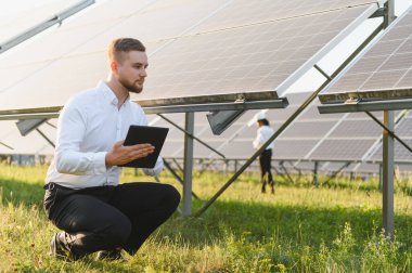 Bir tablet üzerinde güneş çiftliği performansını inceleyen adam sürdürülebilir enerji ve yeşil enerjiye doğru çalışıyor.