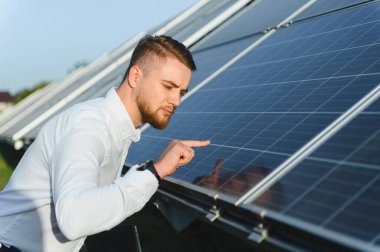Adam güneş paneli hücrelerini kontrol ediyor, düzgün işlemesini ve temiz bir gelecek için sürdürülebilir enerji üretimini sağlıyor