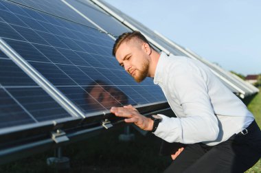 Bir dizi güneş panelini inceleyen mühendis, performansı kontrol ediyor ve verimli bir yenilenebilir enerji üretimi sağlıyor