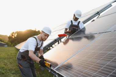 Bir alana güneş panelleri kuran işçiler, yenilenebilir enerji üretimine ve sürdürülebilir enerji üretimine katkıda bulunuyorlar