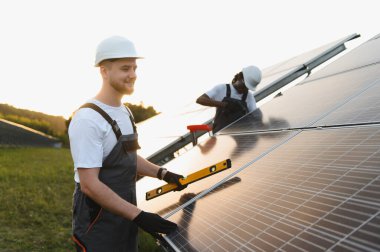 İki mühendis yeşil alana sürdürülebilir temiz enerjiye katkıda bulunan güneş panelleri kuruyor.